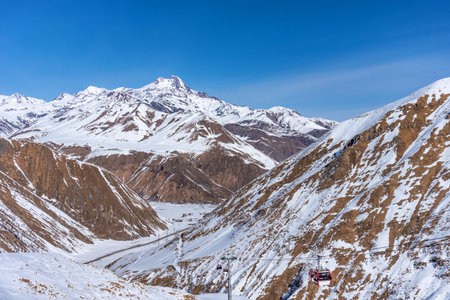 Magnificent panoramic view of snowy mountains in winter, with a sunny and a bright blue skyの写真素材