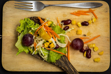 Fresh spring salad with rucola, feta cheese, red onion and pomegranate seeds in black bowl on chalkboard background with free text space.の写真素材