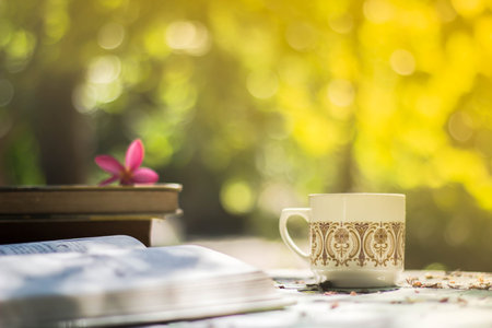 Cup of coffee with flower desk,soft focus background blur book