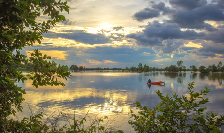Fisherman sits on a red boat fishing for sunlight.の写真素材