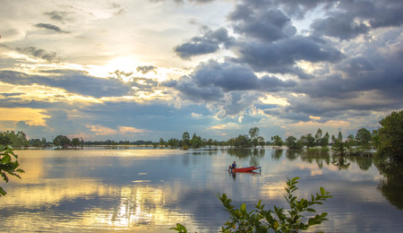 Fisherman sits on a red boat fishing for sunlight.の写真素材