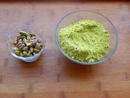 peeled pistachios in a glass bowl and pistachio flourの写真素材