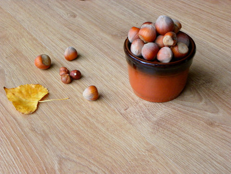 hazelnuts in a bowl and autumn leaves on a wooden table