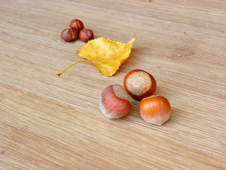 hazelnuts and autumn leaves on a wooden table