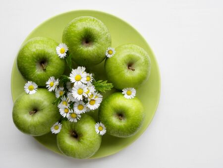 green apples and a bouquet of daisies on a white backgroundの写真素材