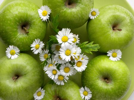 green apples and a bouquet of daisies close-upの写真素材
