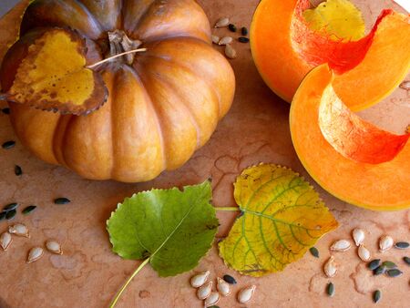 whole pumpkin and autumn leaves on wooden backgroundの写真素材