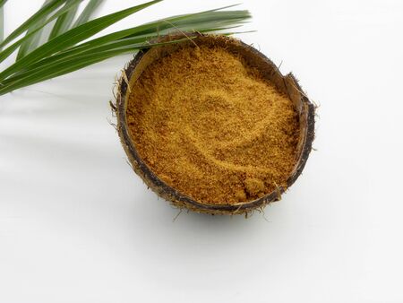 coconut sugar in a bowl of coconut and a sprig of palm on a white backgroundの写真素材