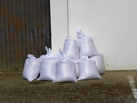 White sandbags loaded with sand on street for later use as flood protection on rainy spring dayの写真素材
