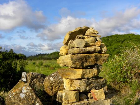 Balanced stones on a background of blue sky and green trees. Stone tower, balanced rock sculpture.の写真素材