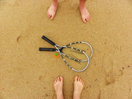 Badminton concept. Badminton rackets, shuttlecock and male and female feet on sand background. Top view of space for text.の写真素材