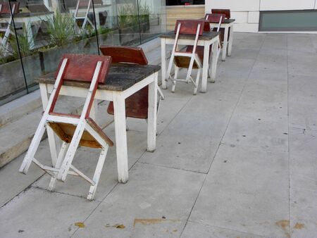 Wooden tables and chairs in a street cafe. Empty tables in a street cafe. Cafe without visitors. Cafe is closedの写真素材