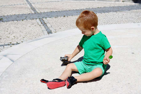 A three-year-old boy plays with a toy car outdoors on a sunny summer day. Kids toys. The child plays with toys.の写真素材