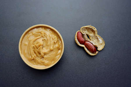 Peanut butter in a round wooden bowl on a gray background.の写真素材