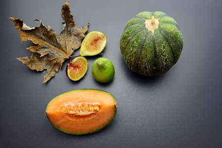 A slice of ripe and juicy cantaloupe melon and sweet figs on a gray background. Autumn still life with melon and figs. Autumn fruits.の写真素材