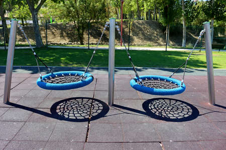 Blue and black hanging round wicker rope swing with wicker seat in children's playground. Swing spider.の写真素材