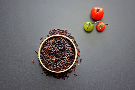 Black rice in a round wooden bowl on a gray background.の写真素材
