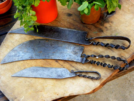 Collection of vintage metal knives on a wooden background.の写真素材