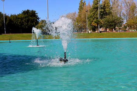 A fountain with splashes and drops of water works. Fountains in a pond with blue water.の写真素材