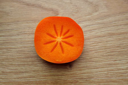 Orange persimmon in a cut on a wooden background.の写真素材