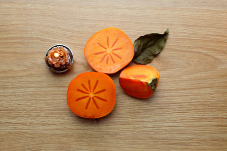 Slices of ripe orange persimmons on a wooden background. Orange autumn fruits.