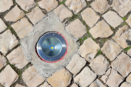 Round led lamp for night illumination of buildings and objects, with a metal rim and durable tempered glass, built into the stone surface of the sidewalk pedestrian zoneの写真素材