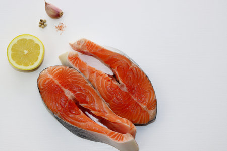 Two large and fatty salmon steaks on a white background. Salmon, salt, pepper and lemon.の写真素材