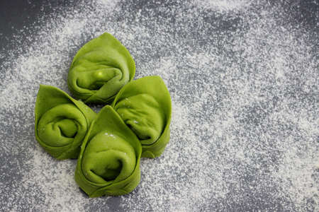 Raw homemade green tortellini on a background of scattered flour.の写真素材