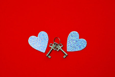 Two silver hearts and keys on a red background. Valentines Day. Holiday concept.の写真素材