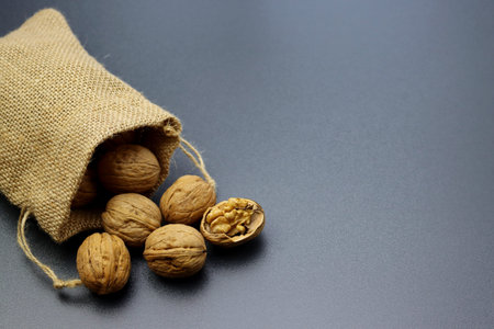 Whole walnuts in a linen bag close up on a gray background
