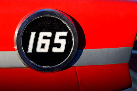 Round plaque with the number one hundred sixty five on a red backgroundの写真素材