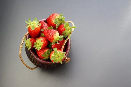 Ripe red strawberries in a wicker basket on a gray background.の写真素材