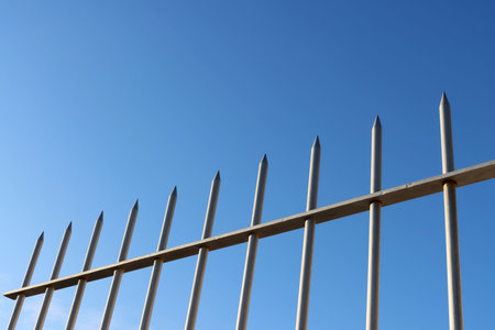 Steel decorative fence with sharp edges against the blue sky. A modern concept.