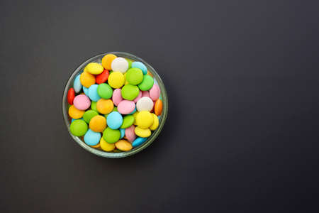 Multicolored sweet candies in a round bowl on a gray background.の写真素材