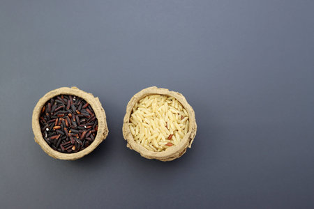 Black and brown rice in round paper bowls on a gray background.の写真素材