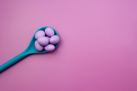Lilac sweet drops in a blue spoon on a pink background.の写真素材