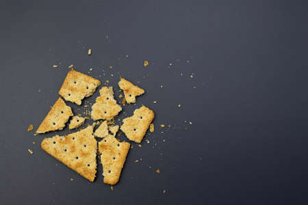 The square cracker is broken into many small pieces. Broken cookies on a gray background.の写真素材