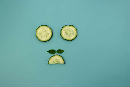 Circles and semicircles of a cucumber with green mint leaves on a light blue background. Funny background.の写真素材