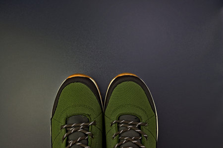 Men's sports shoes from green textiles with laces on a gray background.