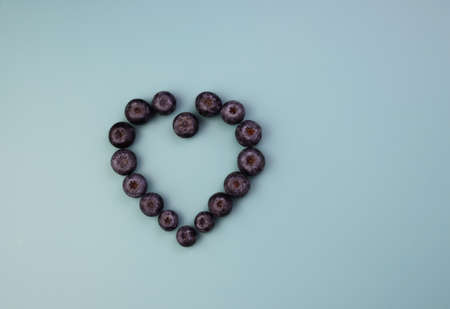 Blueberries are laid out in the shape of a heart. Fresh blueberries on a blue background.の写真素材