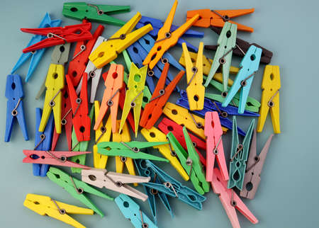 A pile of multi-colored plastic clothespins on a blue background. Bright clothespins backgroundの写真素材