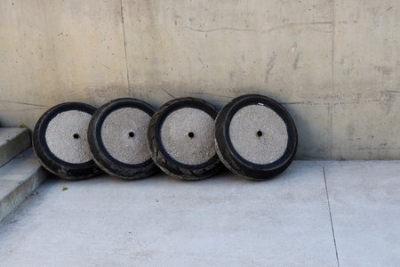 Car tires are filled with cement and stones inside. Round holders for large outdoor umbrellas made...