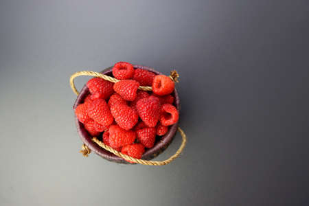 Red ripe raspberries in a wicker basket on a gray background.の写真素材