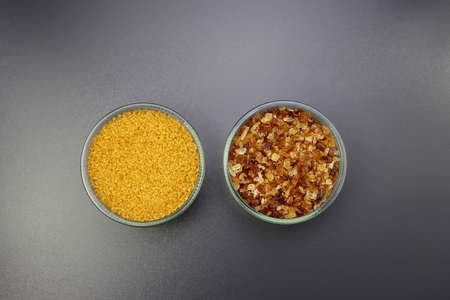 Brown sugar and sugar candy in round bowls on a gray background. Small to large brown sugar crystals.の写真素材