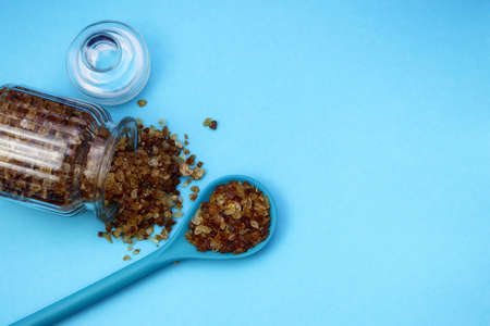 Candy sugar in a glass jar and a blue spoon on a blue background. Brown sugar crystals.の写真素材