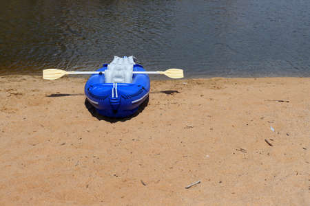 Blue rubber boat and oars on the sandy bank of the river. inflatable boatの写真素材