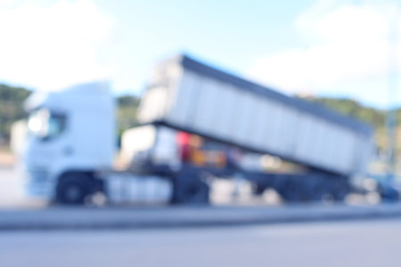 Blurred background with modern cargo truck outdoors in shades of blue, gray, white and sunburst....