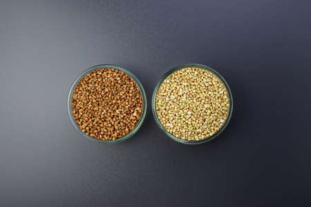 Green and brown buckwheat in round glass bowls on a gray background.の写真素材