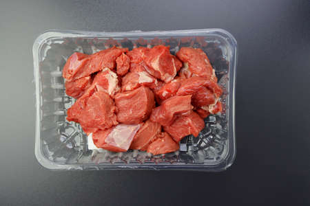 Large pieces of pink veal in a plastic container on a gray background. Fresh red meat.の写真素材