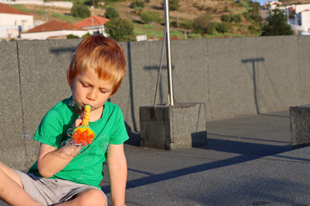 Blond boy makes soap bubbles. A four-year-old boy plays with soap bubbles.の写真素材